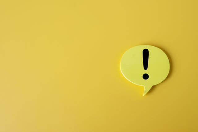 黄色の背景の前にある黄色いビックリマーク
